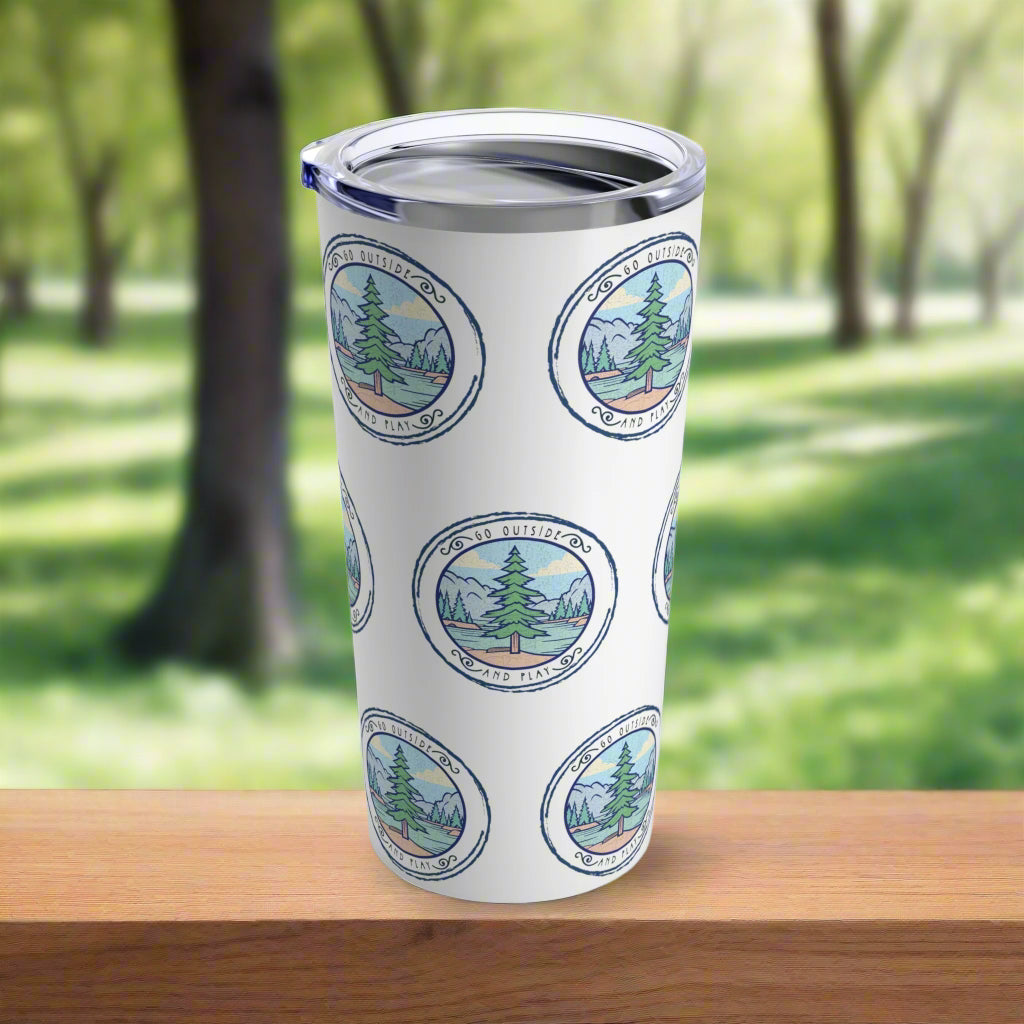 A 20 oz stainless steel tumbler with a clear plastic lid, featuring a design with green trees and the text 'Go Outside and Play'.